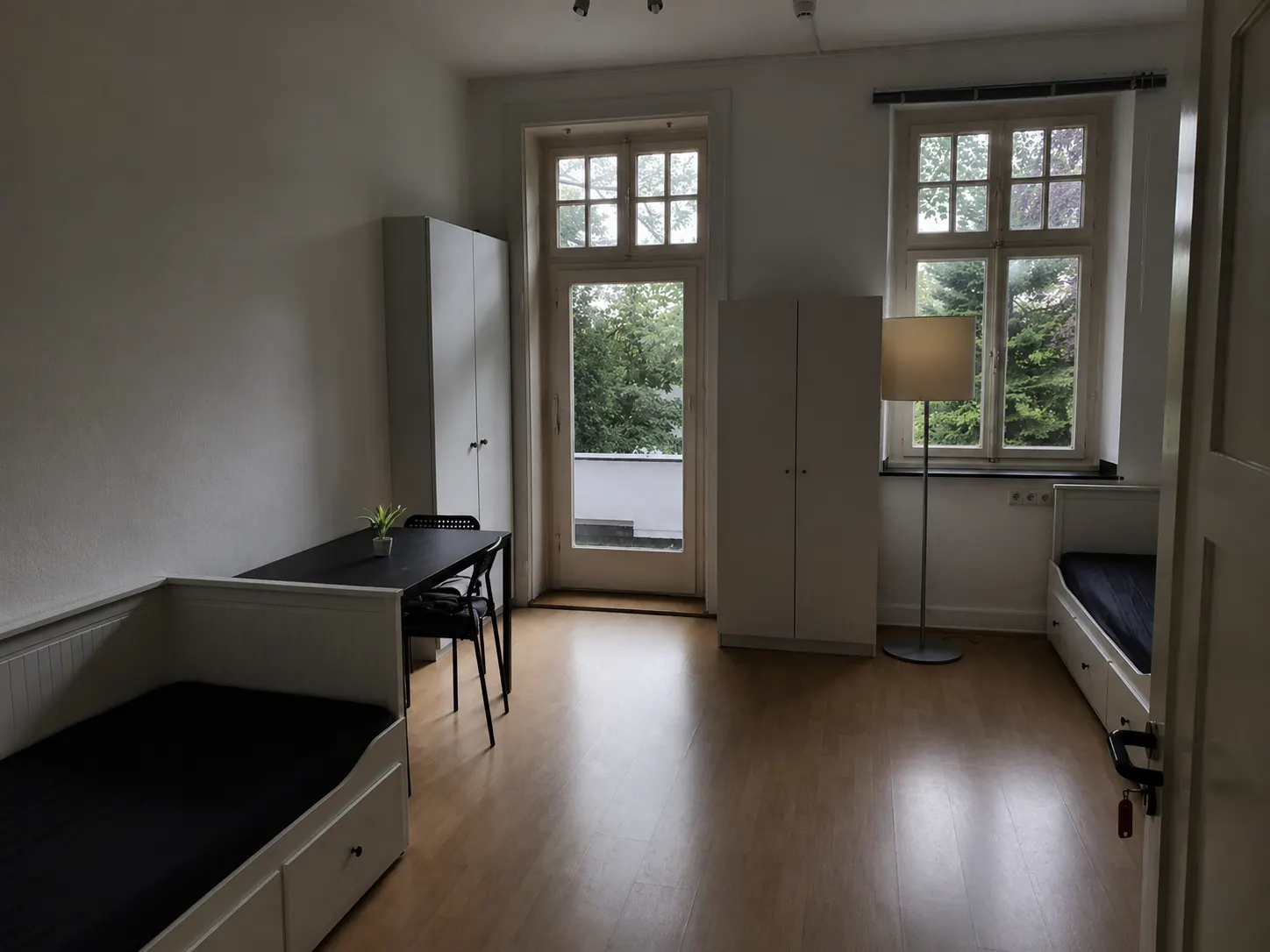 Zimmer mit Einzelbetten, Schränken und Zugang zum Balkon