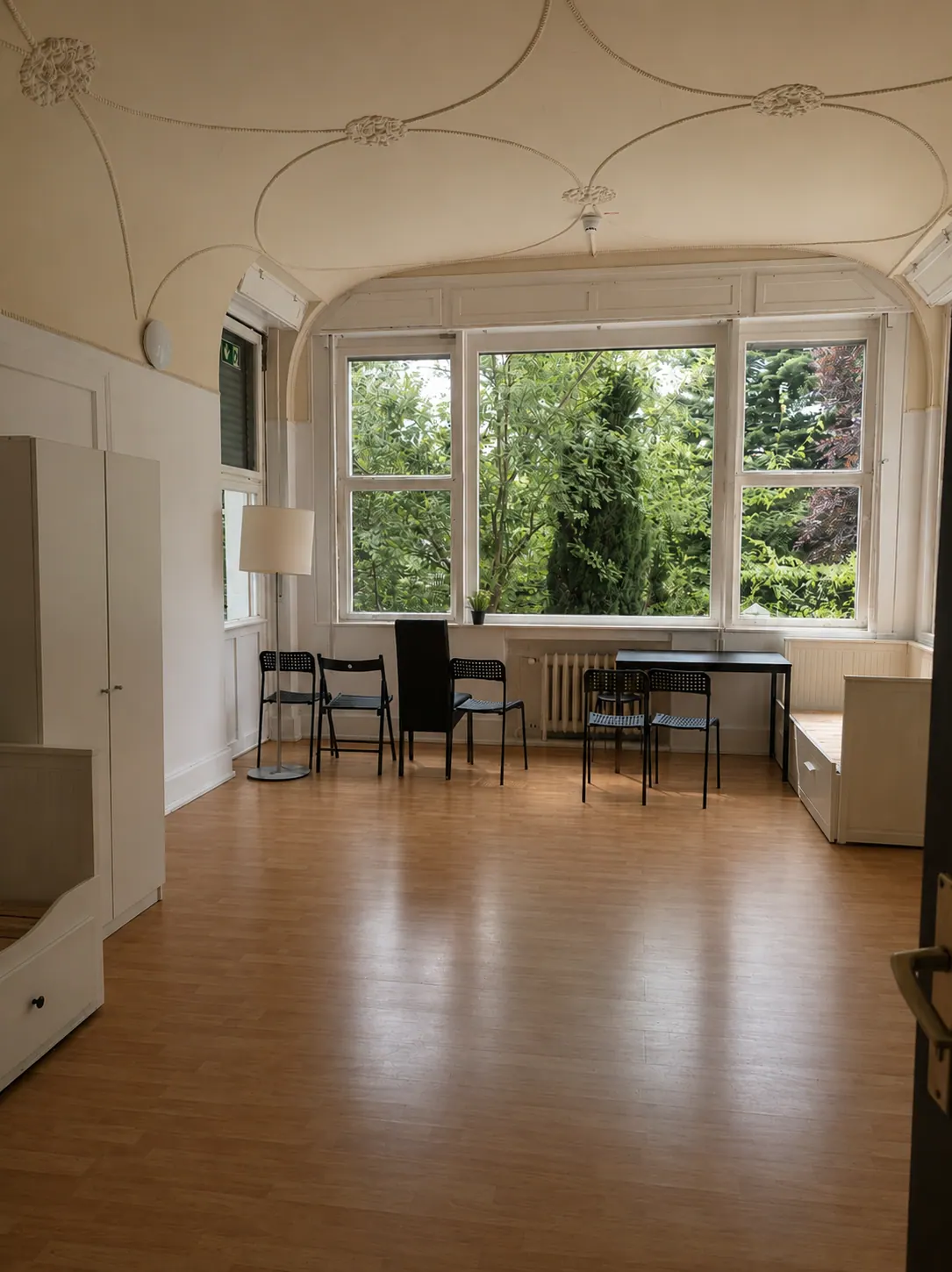 Großes Zimmer mit hohen Fenstern, Betten und Arbeitsbereich