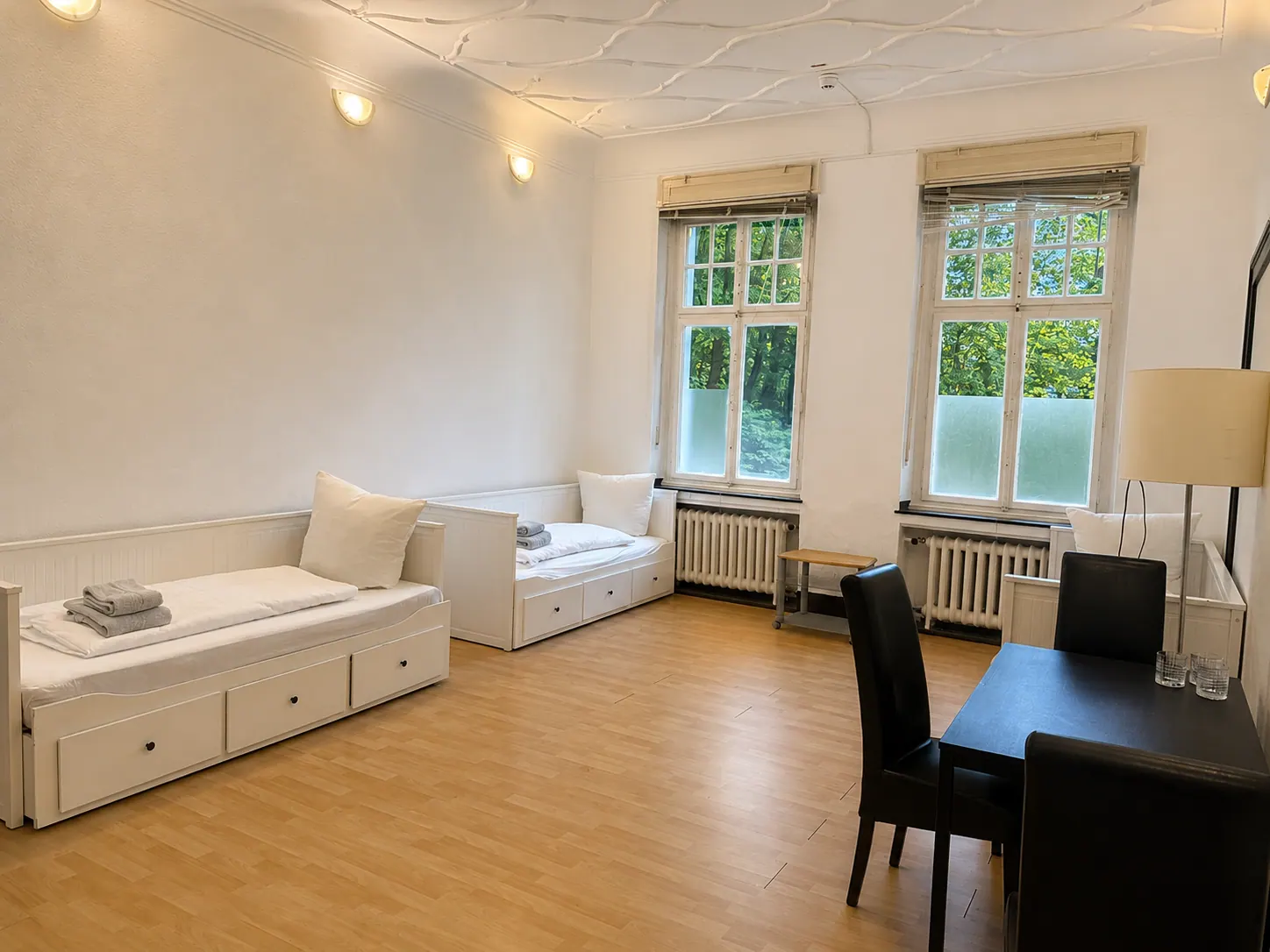 Helles Monteurzimmer mit zwei Betten, Tisch und großen Fenstern