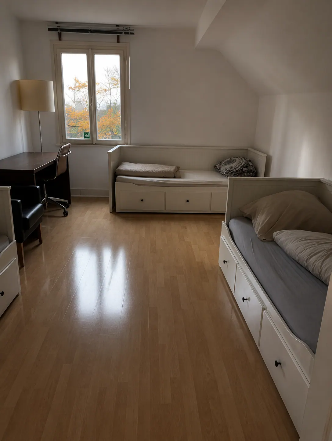 Dachzimmer mit mehreren Betten und Arbeitsplatz