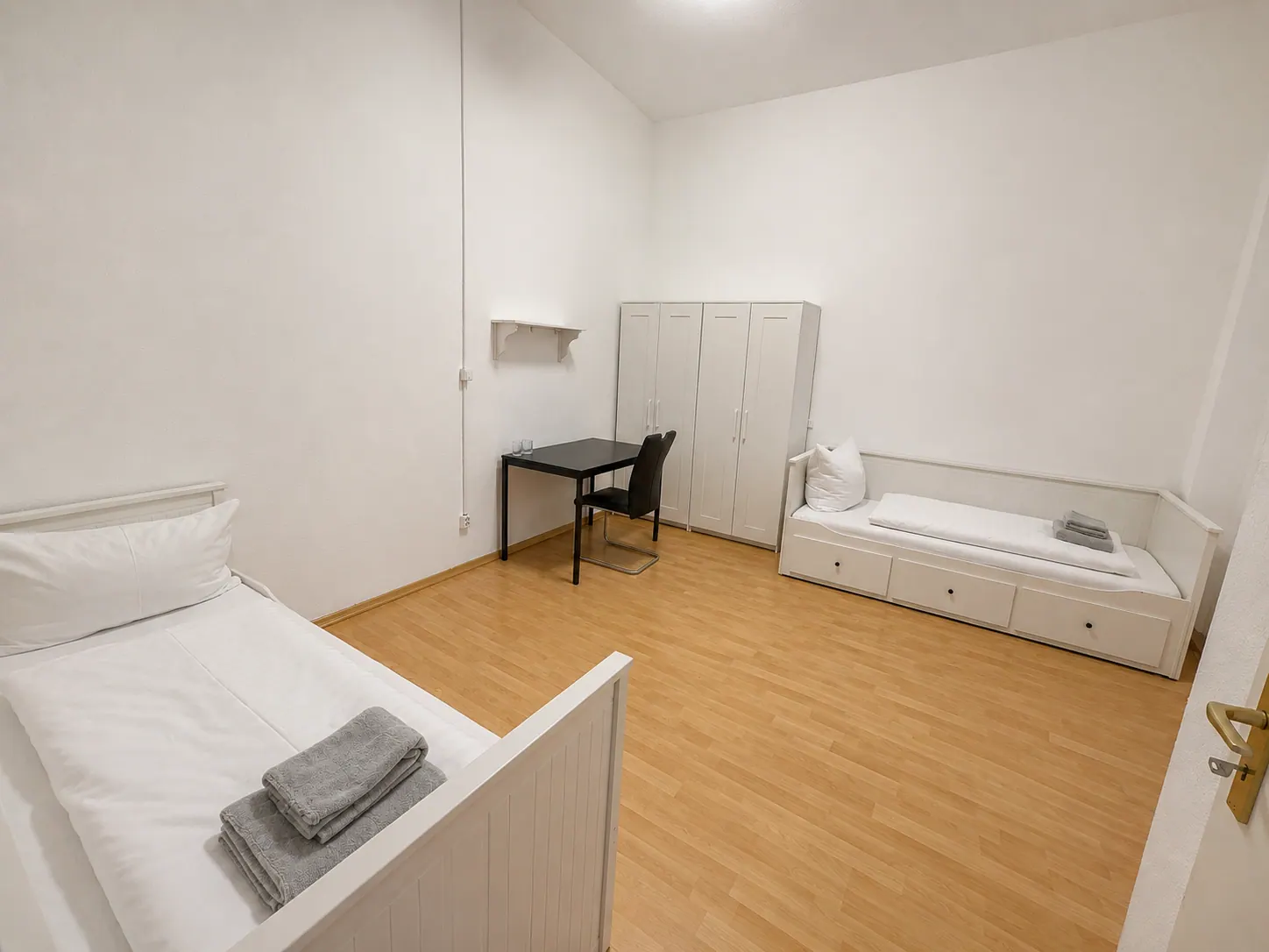 Monteurzimmer mit zwei Einzelbetten, Schrank und Arbeitsplatz